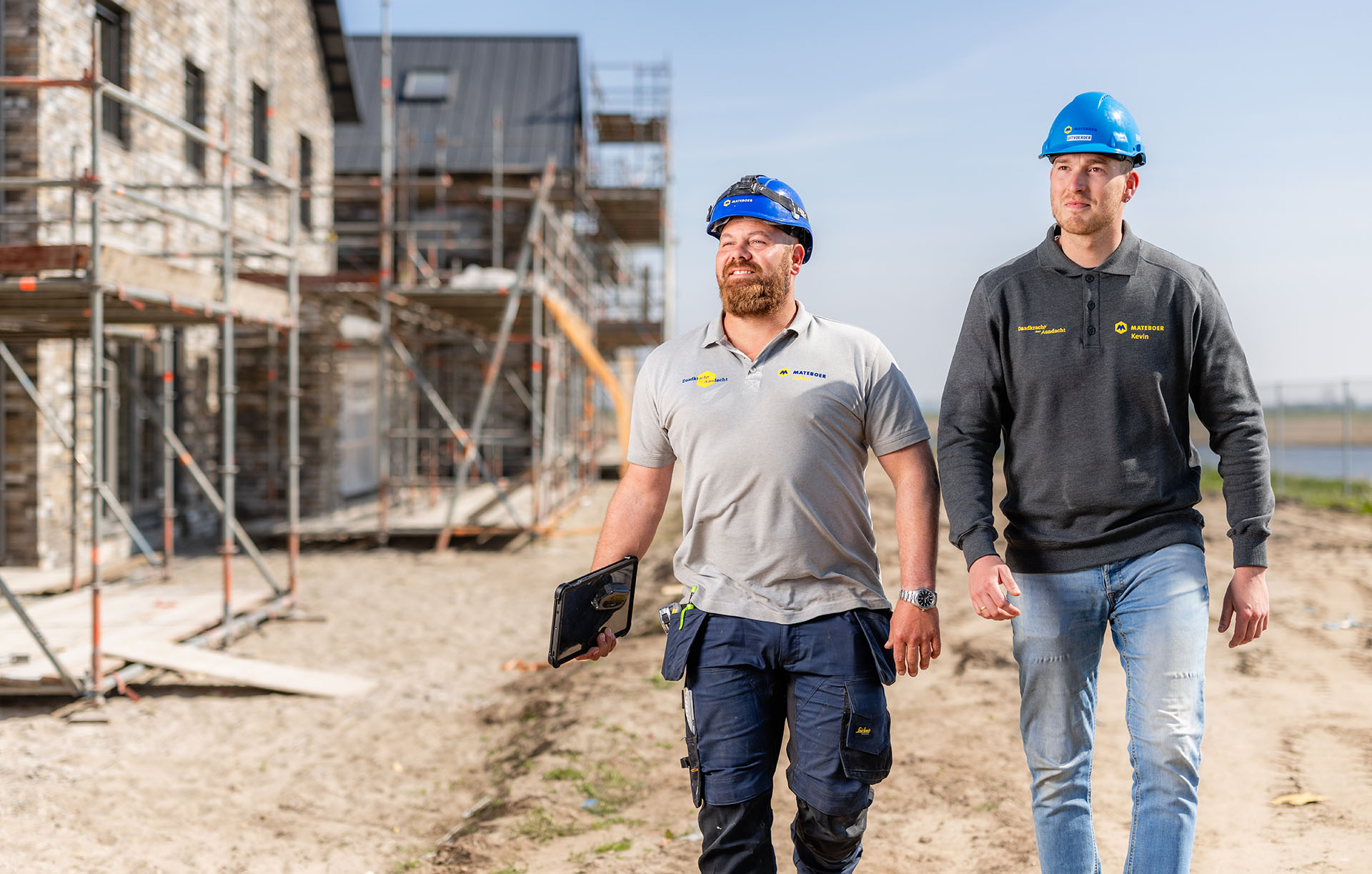 Uitvoerder en timmerman lopen samen over de bouwplaats van een nieuwbouwproject